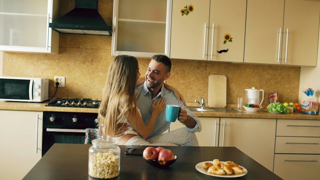 Par sitter tillsammans i köket med en kopp kaffe vid frukostbordet