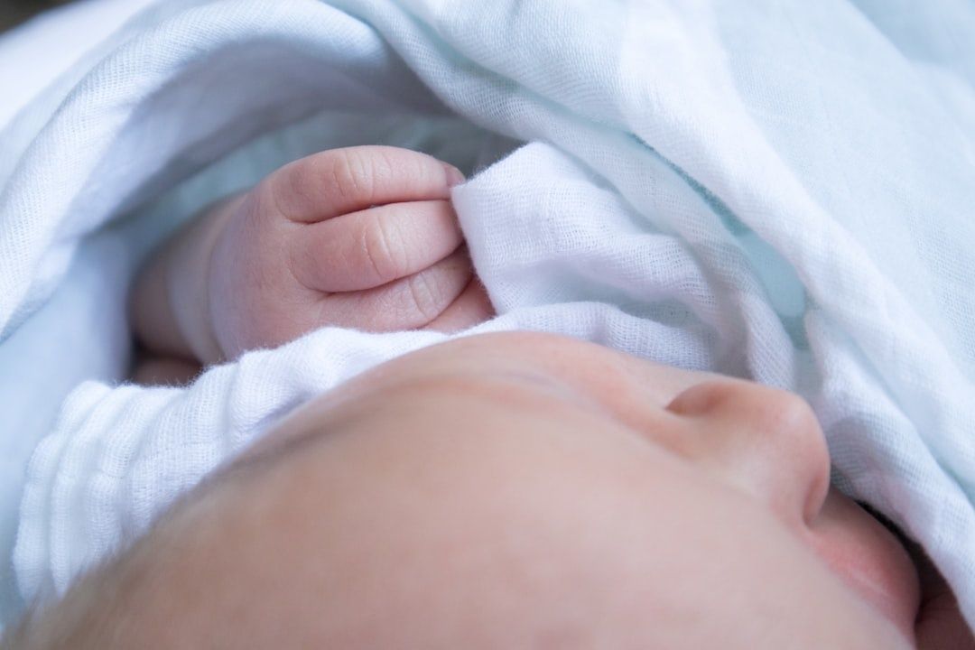 Närbild av en nyfödd bebis insvept i en mjuk vit filt