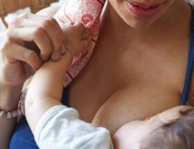 Närbild av mamma som ammar ett spädbarn med stöd om handen