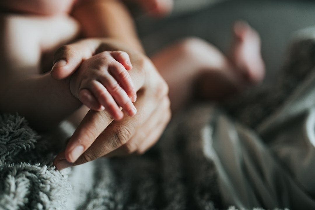 Spädbarnets hand vilar på en vuxens hand under en lugn stund